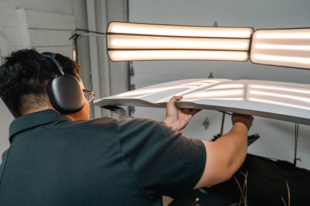 Pro PDR technician removing dent under precision lighting