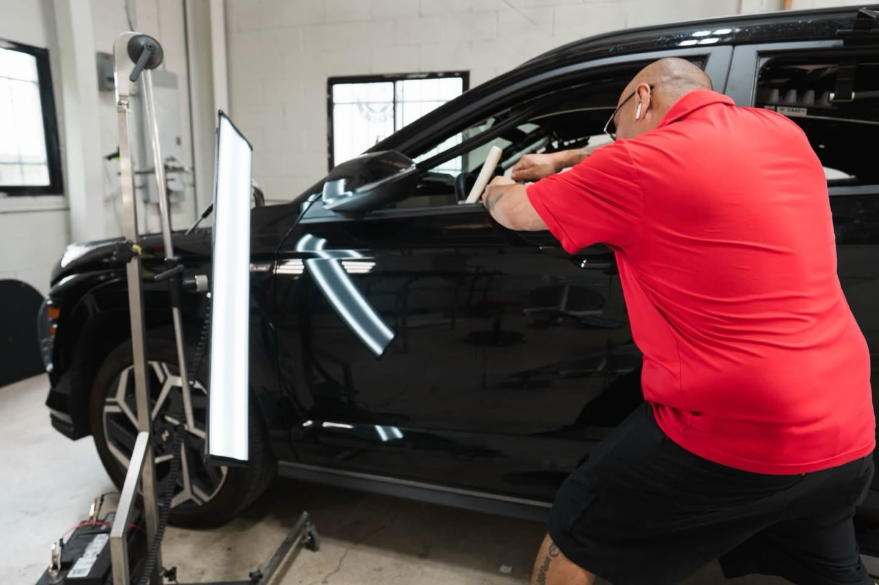 Pro PDR technician working a body-line dent on a black SUV under precision lighting